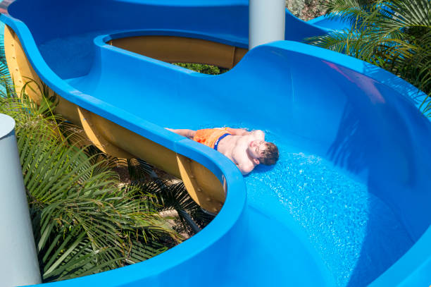 Boy Sliding Down a Blue Waterslide This picture shows a top view perspective of a boy sliding down a blue waterslide. top of water slide photos stock pictures, royalty-free photos & images