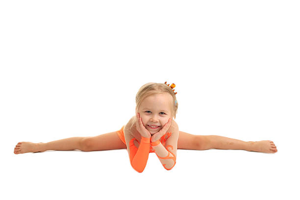 Little ballerina stretching at home, near the window. The girl is aged 7.\n