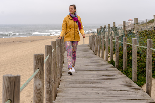 Young beautiful woman walking along the coast walkway in Porto