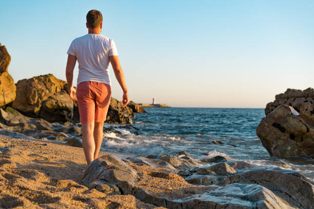 istock Man explores rocky and sandy beach in Matosinhos at sunset 1213929633