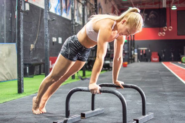 Young woman doing push-ups with bars in gym Young woman doing push-ups with bars in gym blonde female bodybuilders stock pictures, royalty-free photos & images