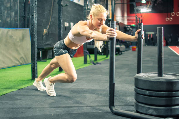 Fit young woman pushing the weight sled at gym Fit young woman pushing the weight sled at gym blonde female bodybuilders stock pictures, royalty-free photos & images