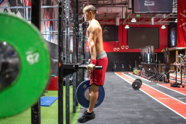 Side view of young man with weight plate doing dip exercise on parallel bars in gym Side view of young man with weight plate doing dip exercise on parallel bars in gym chest dip on athletic workout stock pictures, royalty-free photos & images