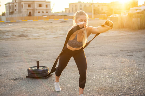 Sporty young woman pulling gym sled with strips on asphalt outdoors Sporty young woman pulling gym sled with strips on asphalt outdoors blonde female bodybuilders stock pictures, royalty-free photos & images