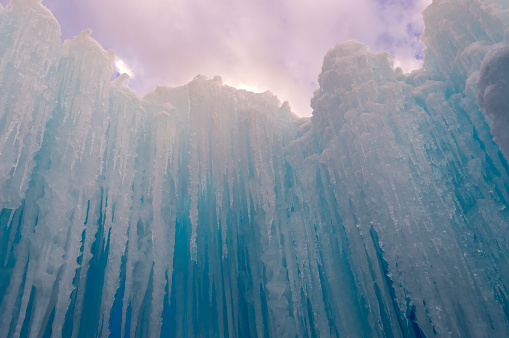 A  view of blue icicles against the background of a dramatic sky.