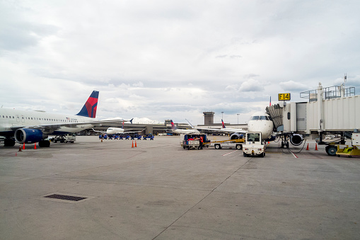 This picture was on a busy day at the Salt Lake City airport with planes parked at the terminal and workers getting them ready for flight.