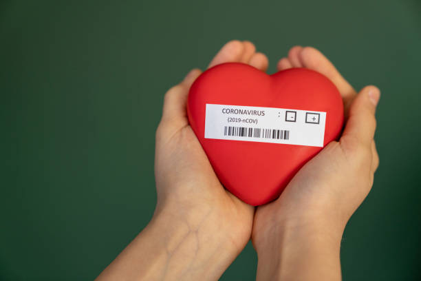 girl holding coronavirus written heart shape in her hand girl holding coronavirus written heart shape in her hand covid 19 positive stock pictures, royalty-free photos & images