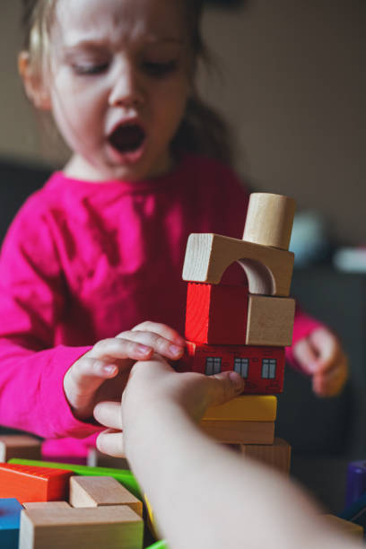 Girl Fights With Brother A three year old is upset by her brother knocking over her tower of blocks. vibrant color lifestyles vertical close up stock pictures, royalty-free photos & images