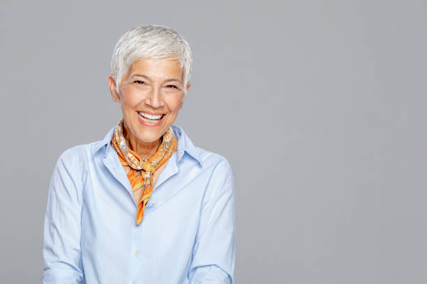 istock Happy senior woman against grey background. 1213937571