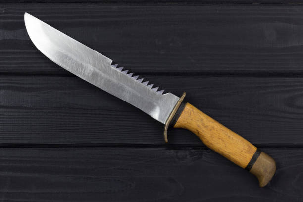 istock Hunting knife on a black wooden background 1213937594