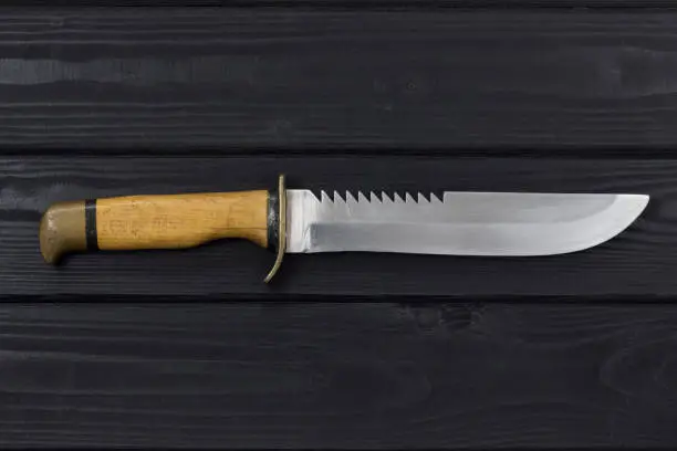 Hunting knife on a black wooden background