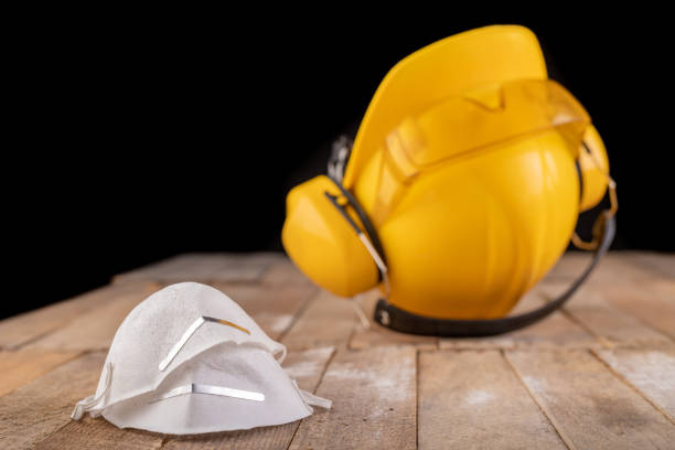 Workwear and protective mask on a wooden table. Protective accessories for the production worker. Dark background.