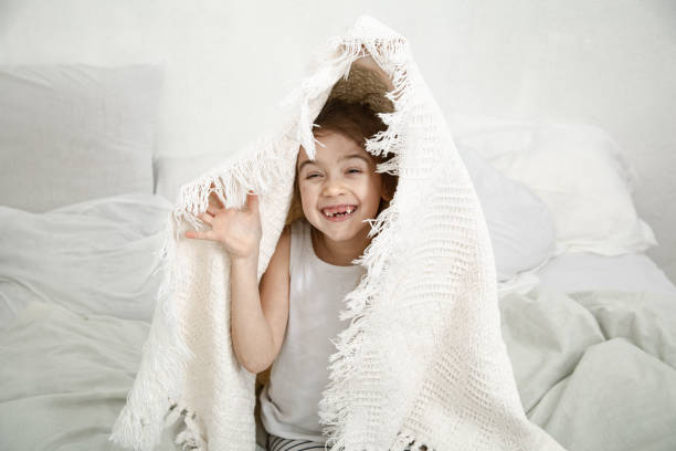 istock Cute little girl playing in bed with a blanket. 1213945192