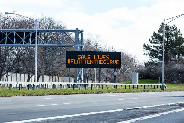 Rochester NY region highway expressway "Save Lives #FlattenTheCurve" road sign after the official New York State directive to state residents to "shelter in place" (stay home) to flatten the curve of the fast spreading coronavirus during the COVID-19 pandemic.