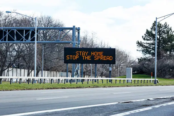 Rochester NY region highway expressway "Stay Home - Stop the Spread" road sign one day after the official New York State directive to state residents to "shelter in place" (stay home) to flatten the curve of the fast spreading coronavirus during the COVID-19 pandemic.