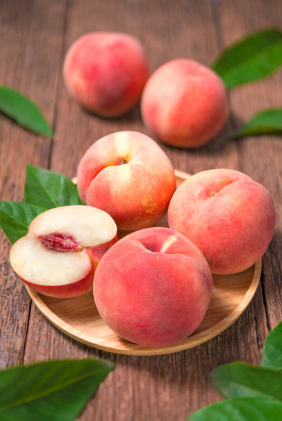 Peaches with leaves on the old wooden table.Fresh white Peaches on wooden Background