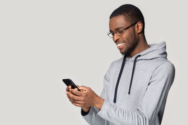 istock Side view smiling African American man using phone, chatting online 1213961313