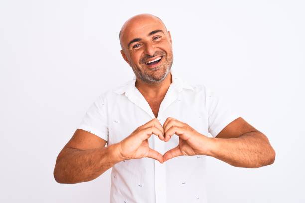 istock Middle age handsome man wearing elegant shirt standing over isolated white background smiling in love showing heart symbol and shape with hands. Romantic concept. 1213961324