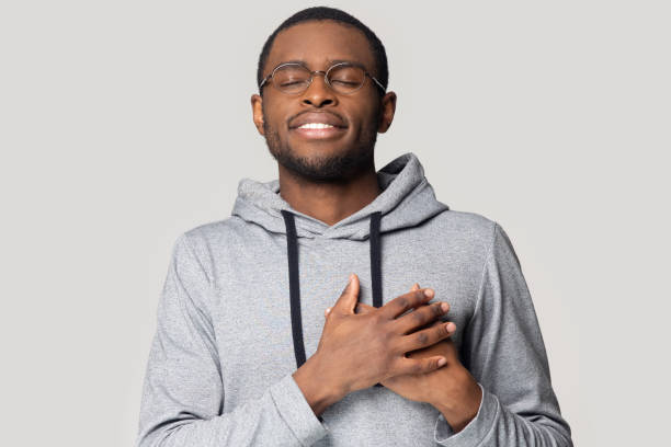 istock Head shot grateful African American man holding hands on chest 1213961369