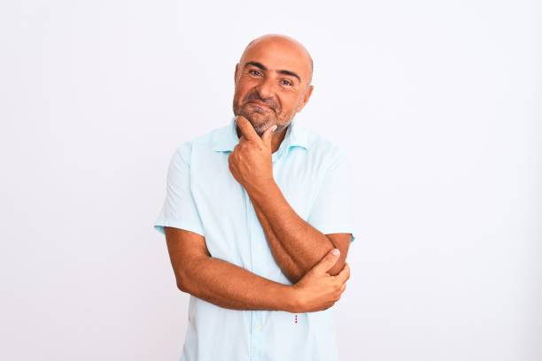 istock Middle age handsome man wearing casual shirt standing over isolated white background looking confident at the camera with smile with crossed arms and hand raised on chin. Thinking positive. 1213962548