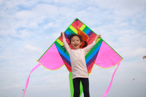 istock asian girls playing and flying kite in a meadow. 1213962921