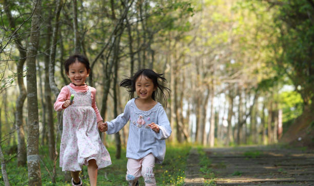 istock two Asian girls running in a forest. 1213966935