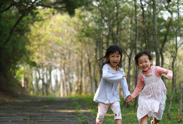 istock two Asian girls running in a forest. 1213967541