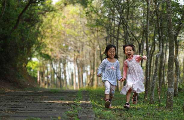 istock two Asian girls running in a forest. 1213967572