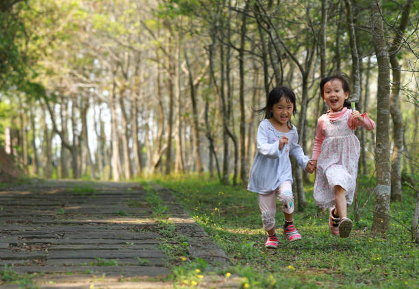 istock two Asian girls running in a forest. 1213967597
