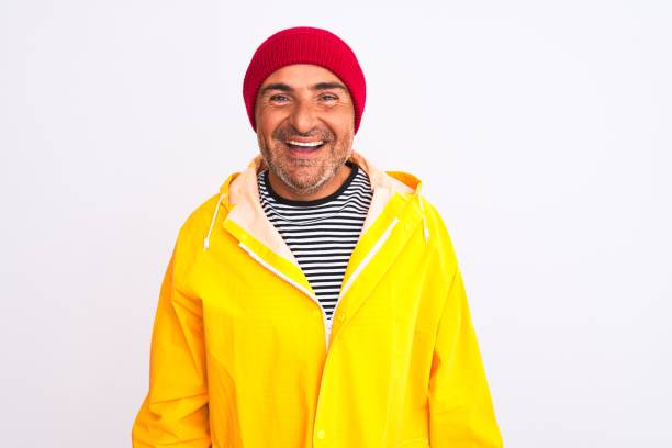 istock Middle age man wearing rain coat and woolen hat standing over isolated white background with a happy and cool smile on face. Lucky person. 1213967901