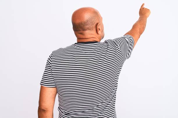 istock Middle age handsome man wearing striped navy t-shirt over isolated white background Posing backwards pointing ahead with finger hand 1213969433
