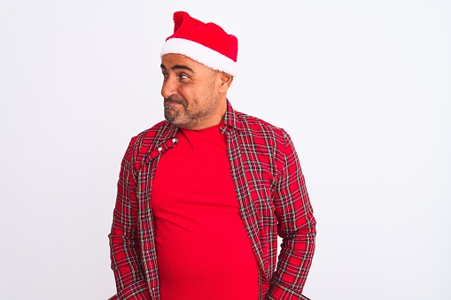 Middle age man wearing Christmas Santa hat standing over isolated white background smiling looking to the side and staring away thinking.