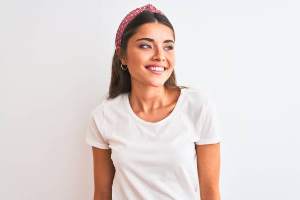 Young beautiful woman wearing casual t-shirt and diadem over isolated white background looking away to side with smile on face, natural expression. Laughing confident. Young beautiful woman wearing casual t-shirt and diadem over isolated white background looking away to side with smile on face, natural expression. Laughing confident. beautiful woman summer stock pictures, royalty-free photos & images