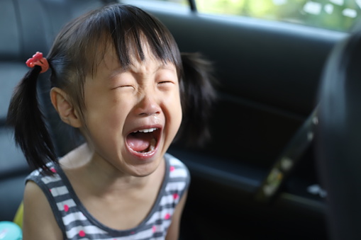a 4-5 years old Asian girl crying and scream in a car.