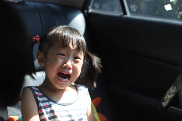 a 4-5 years old Asian girl crying and scream in a car.