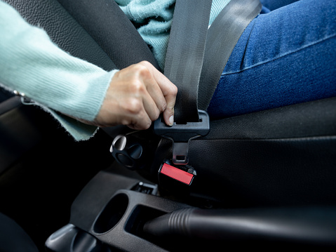 Close up of unrecognizable woman fastening her seat belt - Safety concepts