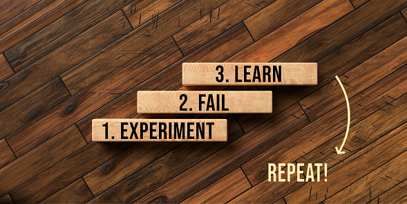 blocks with message EXPERIMENT, FAIL, LEARN and REPEAT on wooden background - 3d rendered illustration