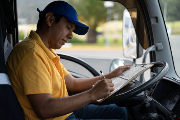 joven conductor latinoamericano llenando un formulario dentro de su camión sonriendo - men latin american and hispanic ethnicity young men smiling fotografías e imágenes de stock
