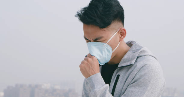 istock man coughs and wears mask 1213992654