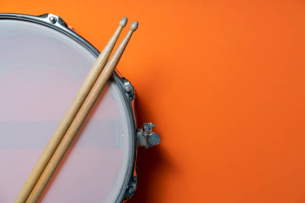 istock Drum stick and drum on orange table background, top view, music concept 1213999316