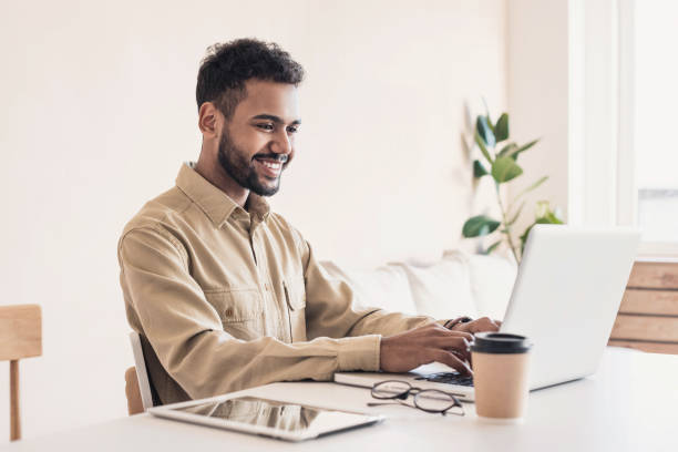 istock Cheerful man using laptop working at home online 1214001332