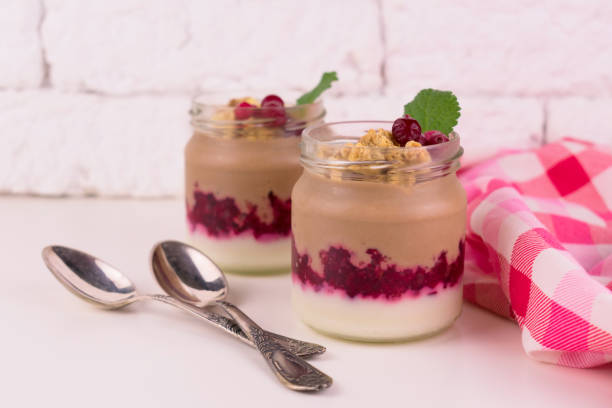 istock Two  chocolate-vanilla pudding with berries and a jar on a white background. 1214005170