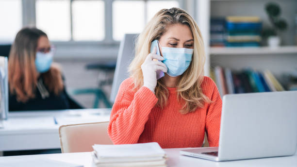istock Colleagues in the office working while wearing medical face mask during COVID-19 1214011606