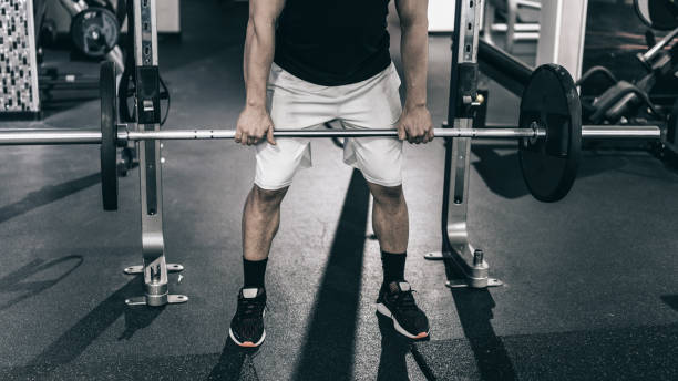 istock Determined man picking up barbell in gym 1214011650
