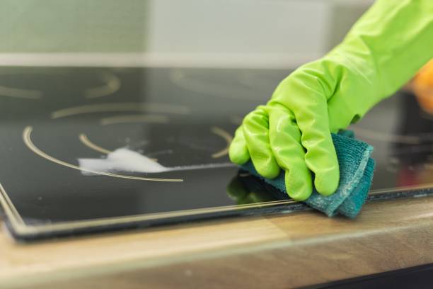 istock Woman hands in gloves cleans kitchen electric ceramic hob 1214012751