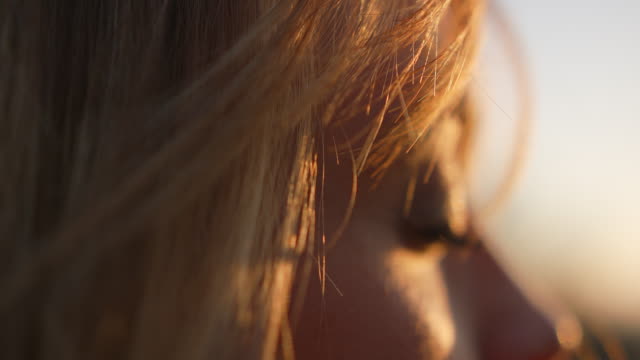 Detail shot of woman's eye, her hair blowing in the wind while she meditates