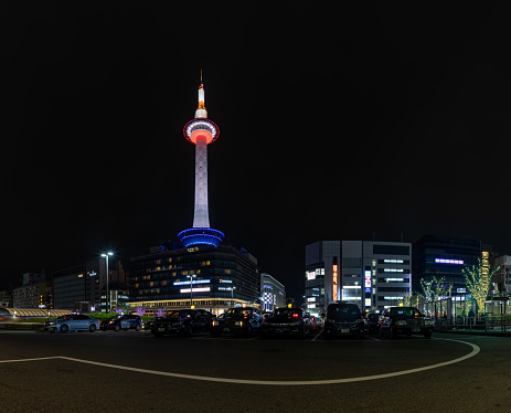 A panorama picture of the Kyoto Tower and the Tokyo Station square at night.