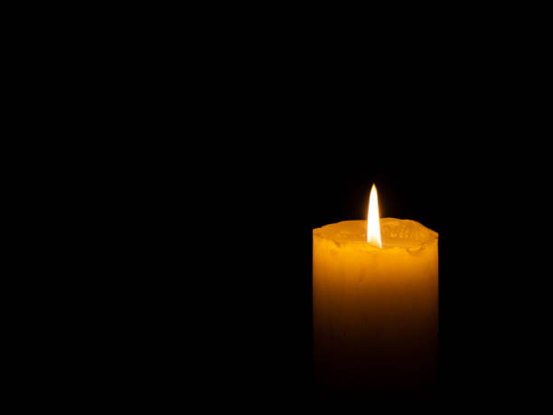 istock Coarse candle lit right with black background 1214015555