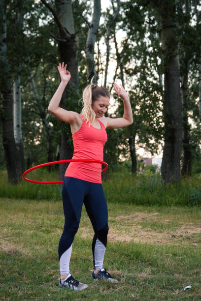 istock Young woman spinning plastic hoop in nature 1214015940