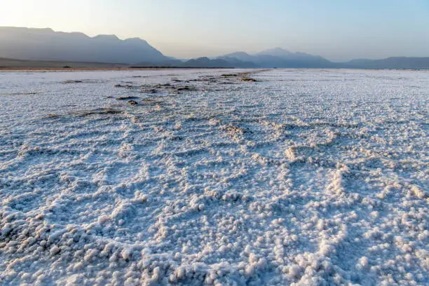 Africa, Djibouti, Lake Assal. Salt texture on the ground with mountains in the background